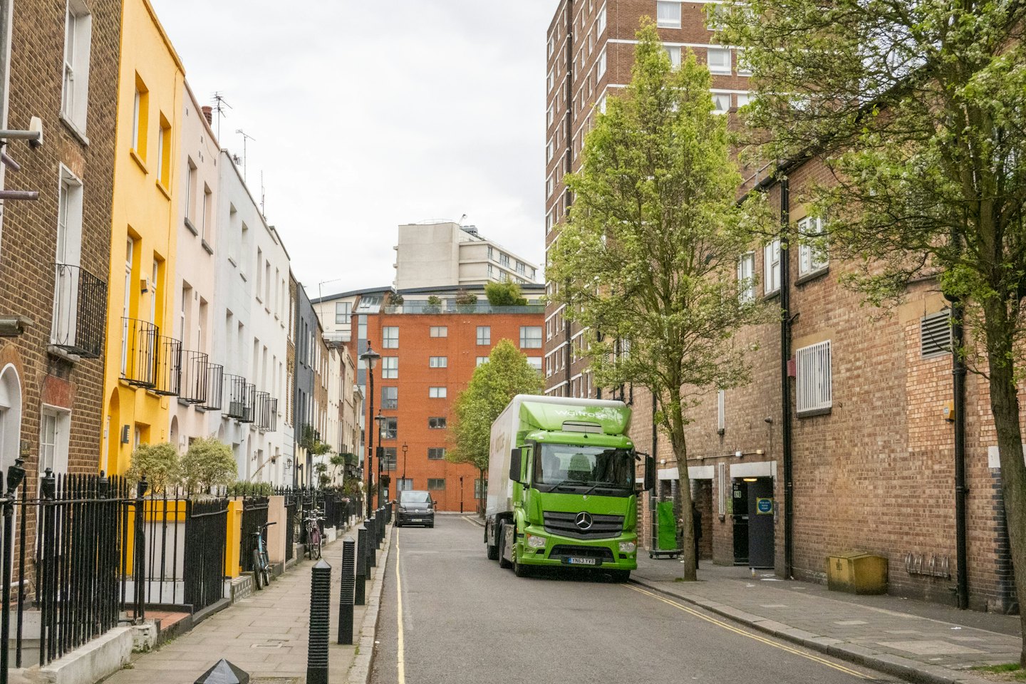 Grüner Lieferwagen parkt in einer schmalen Stadtstraße.